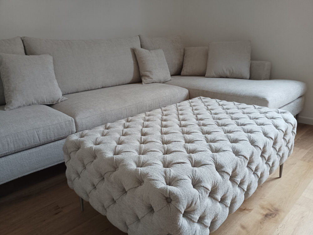 Puof capitonè con divano e penisola in tessuto.