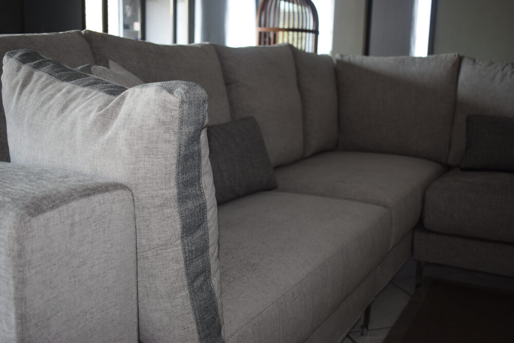 Particolare divano componibile in tessuto grigio.
